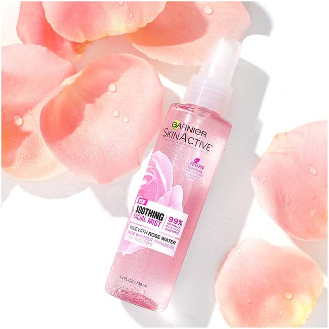 the pink bottle of the facial spray surrounded by rose petals