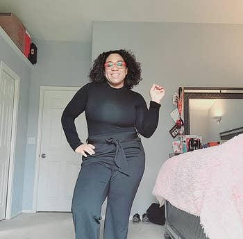 reviewer wearing the black bodysuit tucked into a pair of black straight-leg trousers