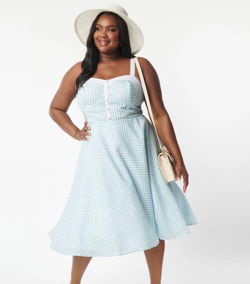 model wearing the blue and white gingham dress with a white hat and purse