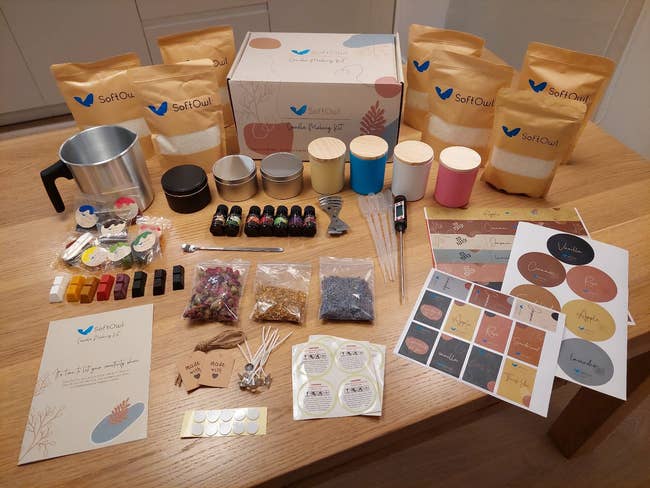 Candle-making kit with wax bags, scents, dyes, labels, and accessories connected a woody table, perfect for DIY enthusiasts