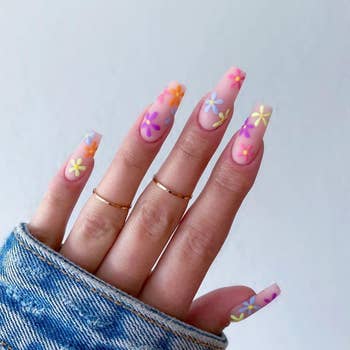 Close-up of a hand with long, manicured nails adorned with colorful flower designs