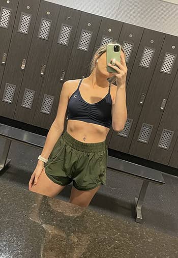 reviewer wearing shorts in green with black sports bra in a locker room