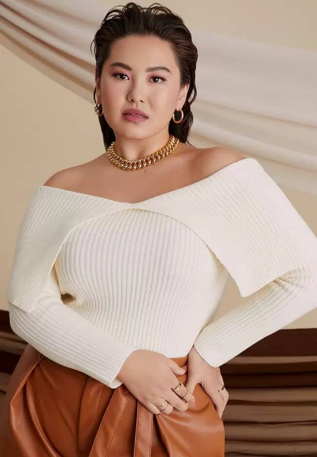 model posing wearing ivory off shoulder sweater