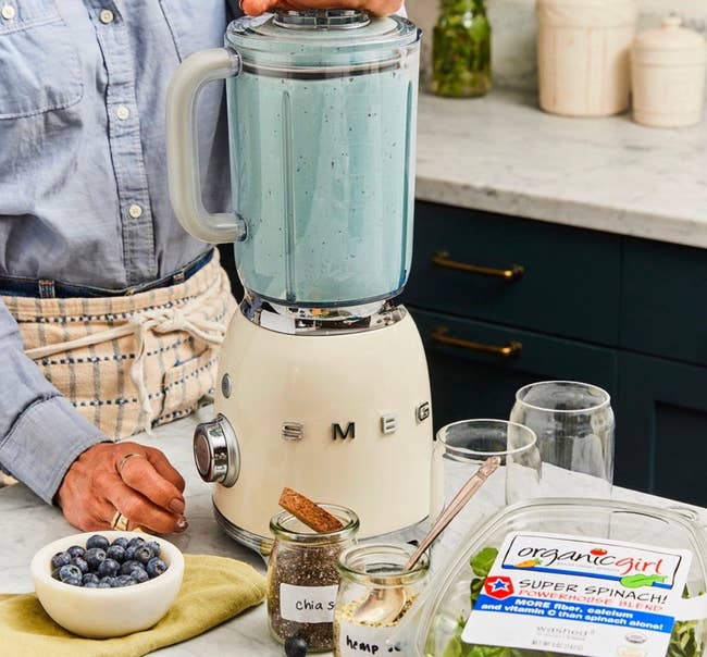 model making a smoothie in a cream Smeg blender