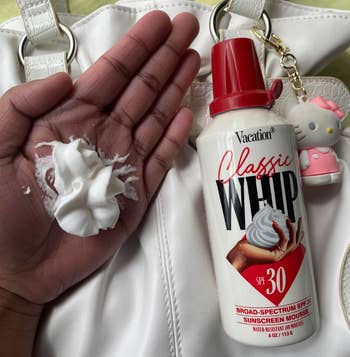 Hand displaying sunscreen mousse from a can labeled 