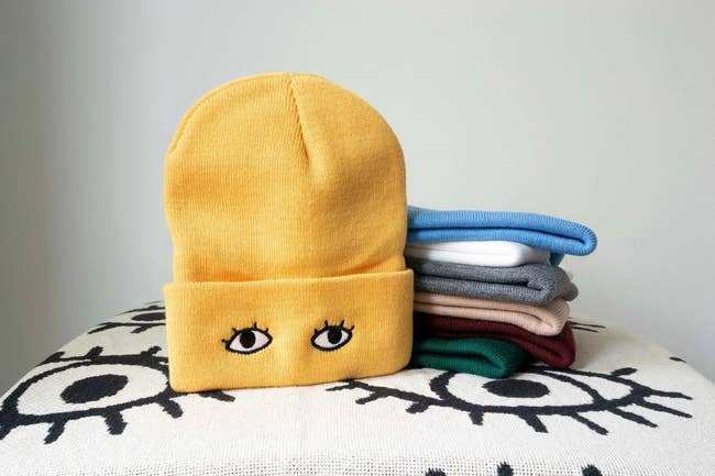 a yellow beanie with eyes embroidered onto the cuff