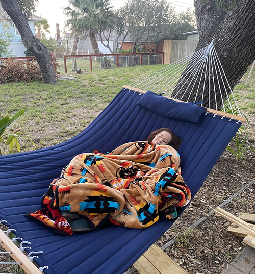 reviewer wrapped up in a blanket on the blue hammock