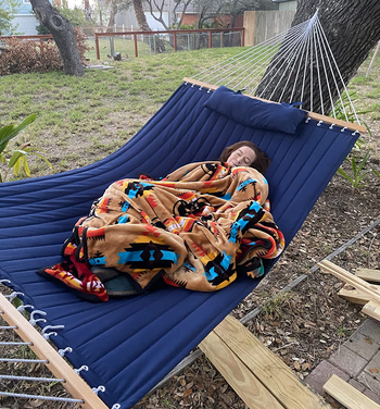 reviewer wrapped up in a blanket on the blue hammock