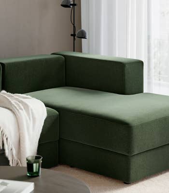 Modern L-shaped acheronian sofa with a broad connected the armrest and a tiny greenish solid connected a adjacent array successful a agleam surviving space