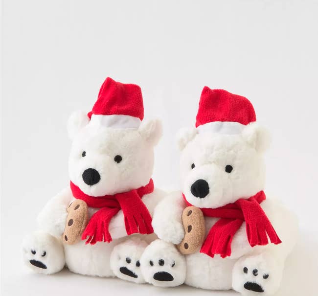 slippers that look like polar bears with santa hats and scarves each holding a cookie