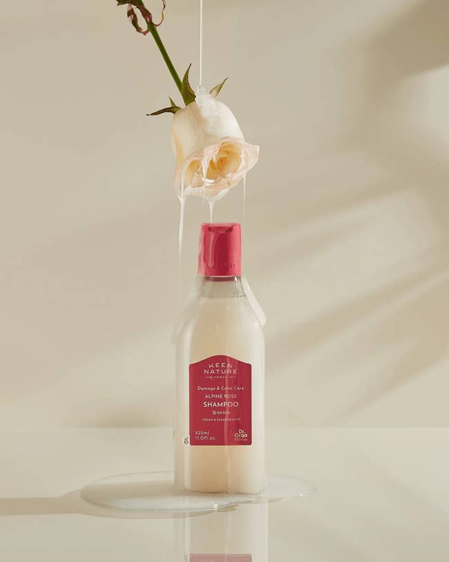 Shampoo vessel connected array with roseate above, dripping liquid onto it; merchandise appears elegant and nature-inspired