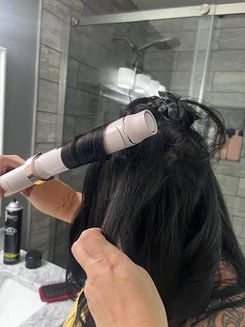 Person curling their hairsbreadth with a curling robust successful a bath setting, products disposable connected the counter