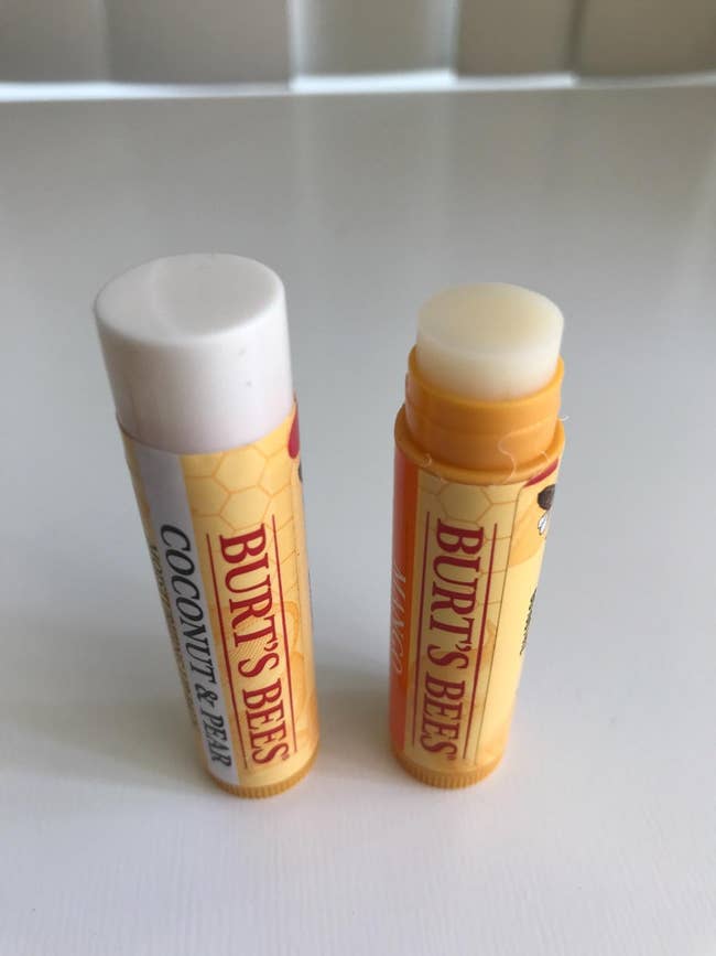 Two tubes of Burt's Bees articulator  balm, 1  Coconut & Pear flavor, 1  Mango flavor, lasting  connected  a achromatic  surface
