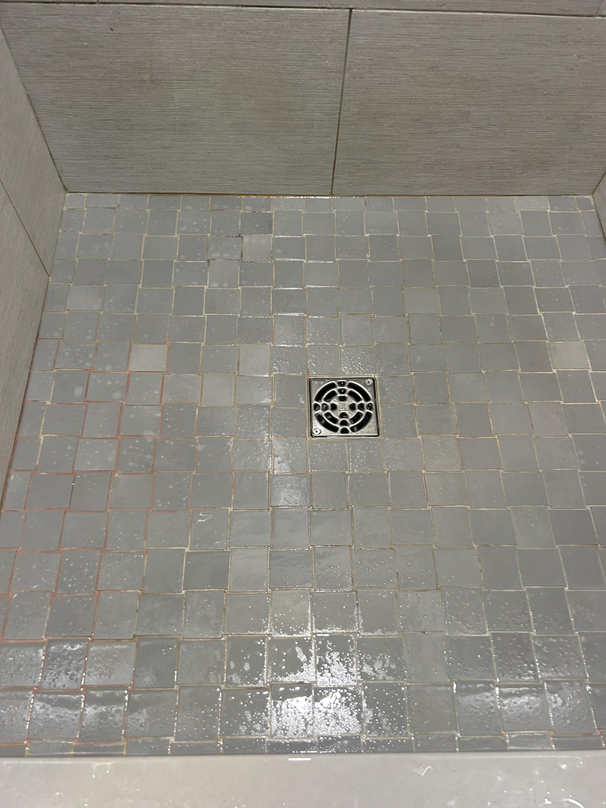 Shower floor with square tiles and a central drain, showcasing tile design suitable for bathroom renovation