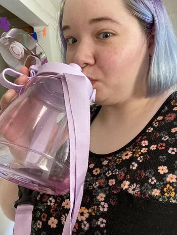 a reviewer sipping a purple jug water bottle