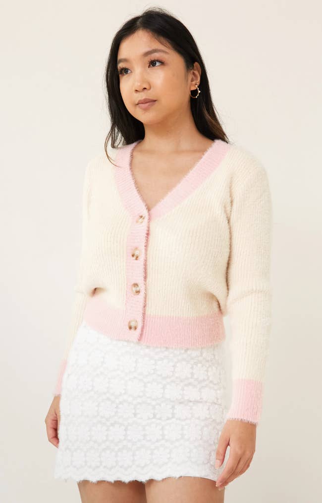 model wearing yellow fuzzy cardigan with pink trim and buttons