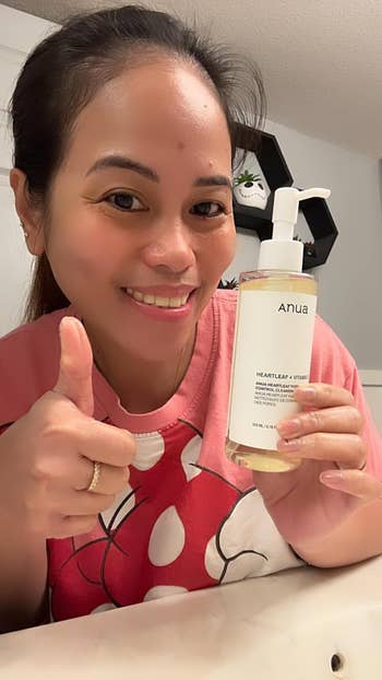 Person holding a vessel  of Anua Heartleaf lipid  cleanser