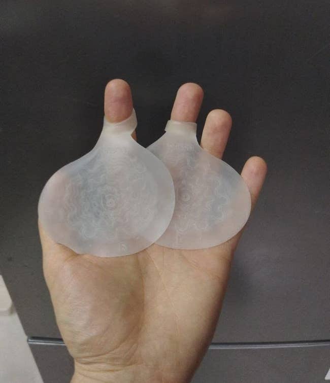 reviewer holding two semi-opaque circular pads with a toe ring
