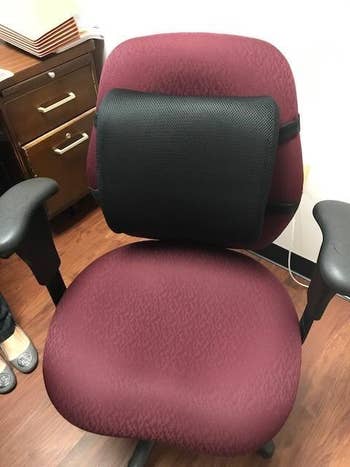 Reviewer's black lumbar support pillow on office chair