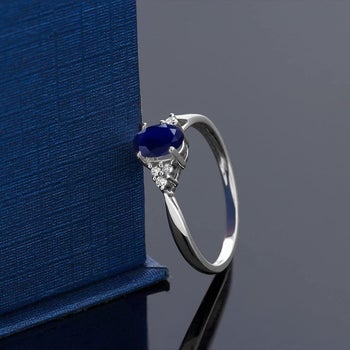a silver ring with a blue sapphire stone in the middle flanked by three small diamonds