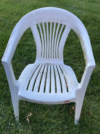 Plastic outdoor seat with a slatted back, placed connected grass