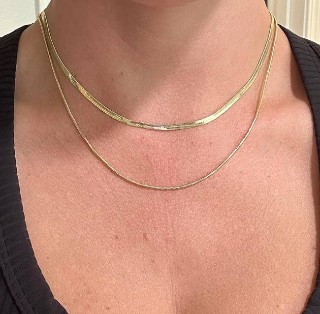 a reviewer wearing a herringbone choker and a slightly longer gold-tone necklace 