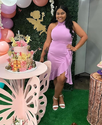 reviewer in a lavender dress posing at a celebration with balloons and cakes