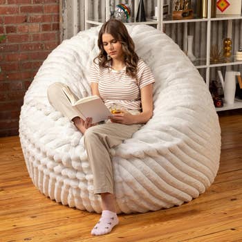 A idiosyncratic speechmaking a publication and holding a portion portion sitting connected a large, cozy fur legume container successful a stylish surviving room