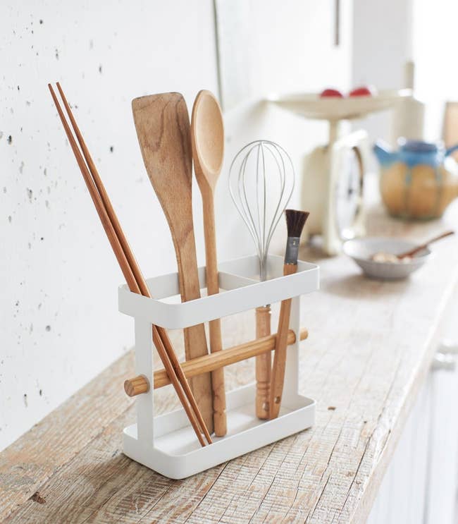 chopsticks, a wooden spoon, a wooden spatula, a brush, and a whisk stored upright in the utensil holder