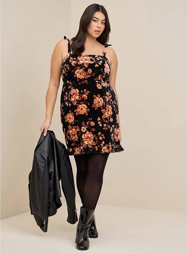 model wearing the black floral print dress with black tights and boots