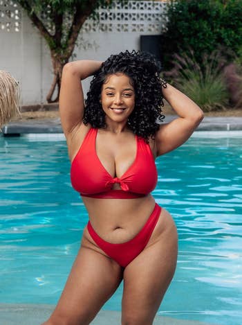 model in a red bikini posing by a pool