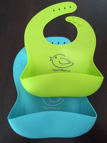 reviewer's two silicone bibs in green and blue