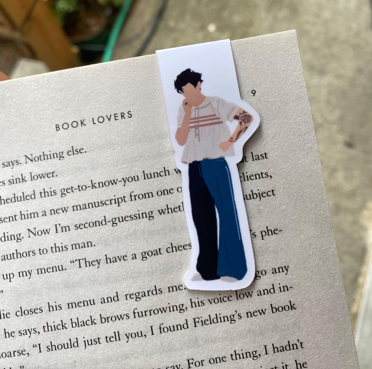 An illustrated Harry Styles bookmark on a book page