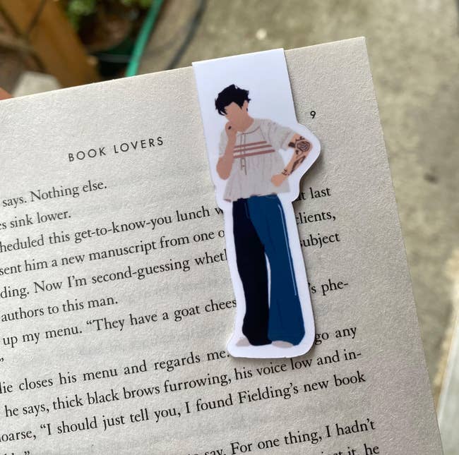 An illustrated Harry Styles bookmark on a book page 