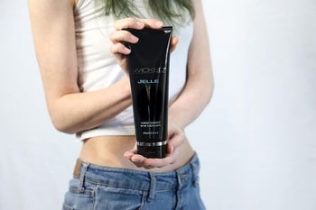 Model holding black tube of Wicked Sensual Care Jelle lubricant