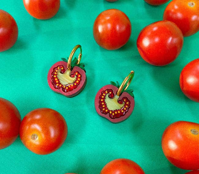 Tomato-shaped earrings displayed among real tomatoes