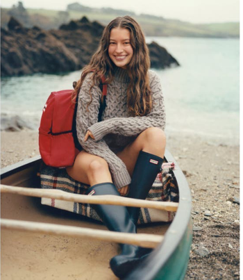 model sitting in canoe wearing tall black Hunter rain boots