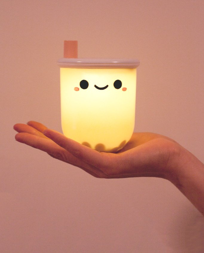 hand holding the light that looks like a boba tea cup with a happy face, with faux boba pearls inside