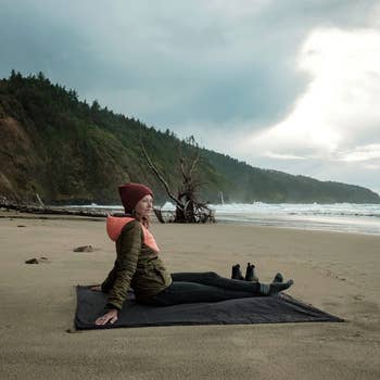model sitting on beach on black blanket