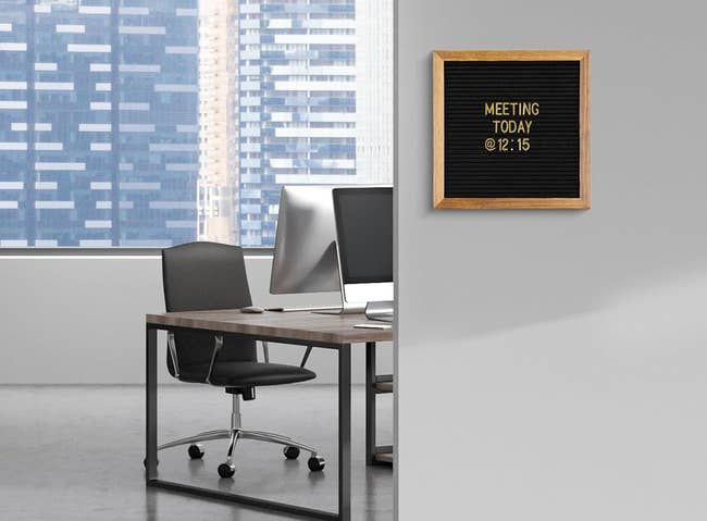 Office space with a desk and computer; wall-mounted sign reads,