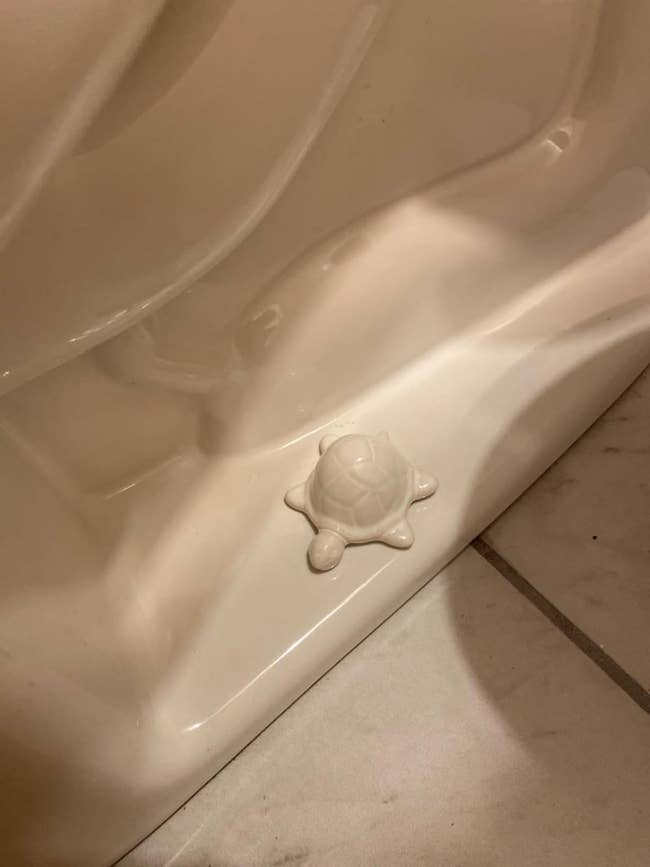 White ceramic turtle figurine placed connected a bath toilet bolt