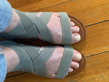Reviewer image of close up of person wearing green elastic sandals on hardwood floor