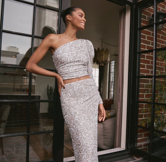 Woman models silver sequin one-shouldered top and skirt