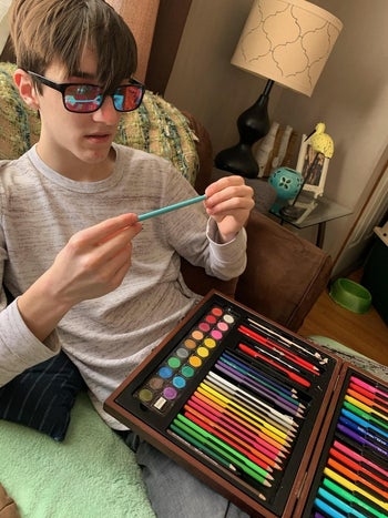 Reviewer's teenager wearing the glasses and looking at colored pencils in wonder