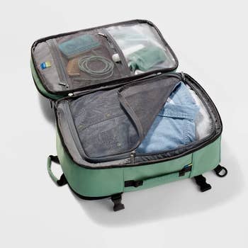 Open suitcase with clothes and items, suggesting packing for a trip. Ideal for travel prep articles