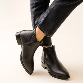 Person wearing black ankle boots paired with cuffed jeans