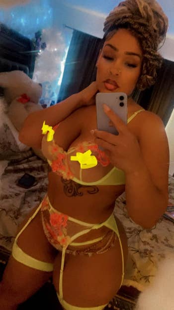 Person takes a selfie successful mirror, wearing yellowish floral lingerie acceptable with bra, garter belt, and underwear.