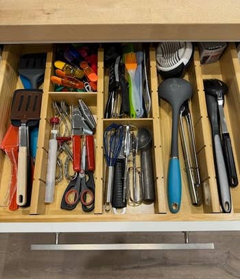 Same drawer filled with assorted kitchen utensils like spatulas, whisks, and scissors in a more orderly fashion