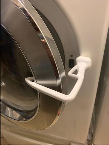 A small white angled door stopper propping open a reviewer's front load washer door 