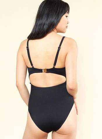 a model wearing the cut out one piece in black
